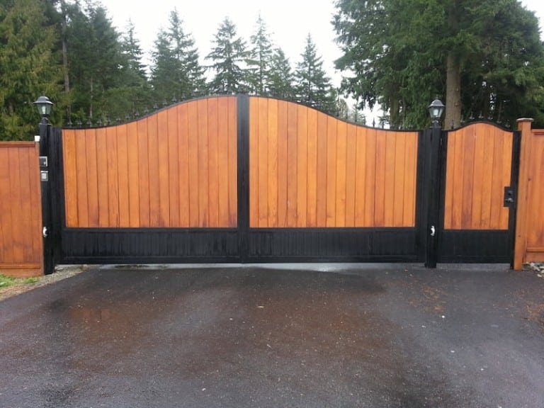 The wooden gate has a black frame, two sections, and a curved top.