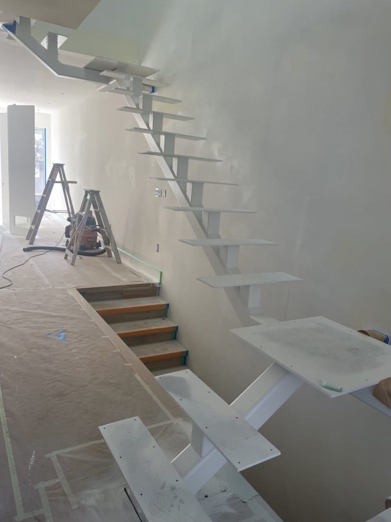 White metal staircase structure being installed, ready for steps to be added.