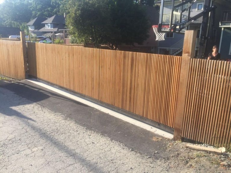 The wooden doorway gate operates on a sliding mechanism, featuring vertical slats and supported by sturdy posts.