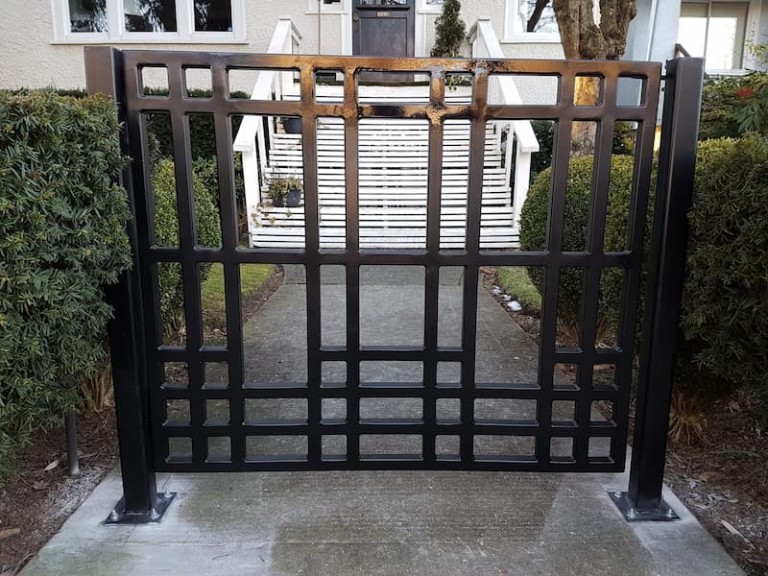 Modern pedestrian gate with a geometric grid pattern, installed at a residential entrance pathway.