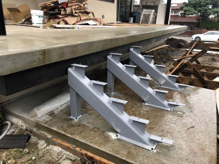 Steel staircase supports installed under a concrete deck, ready for step installation in an outdoor setting.