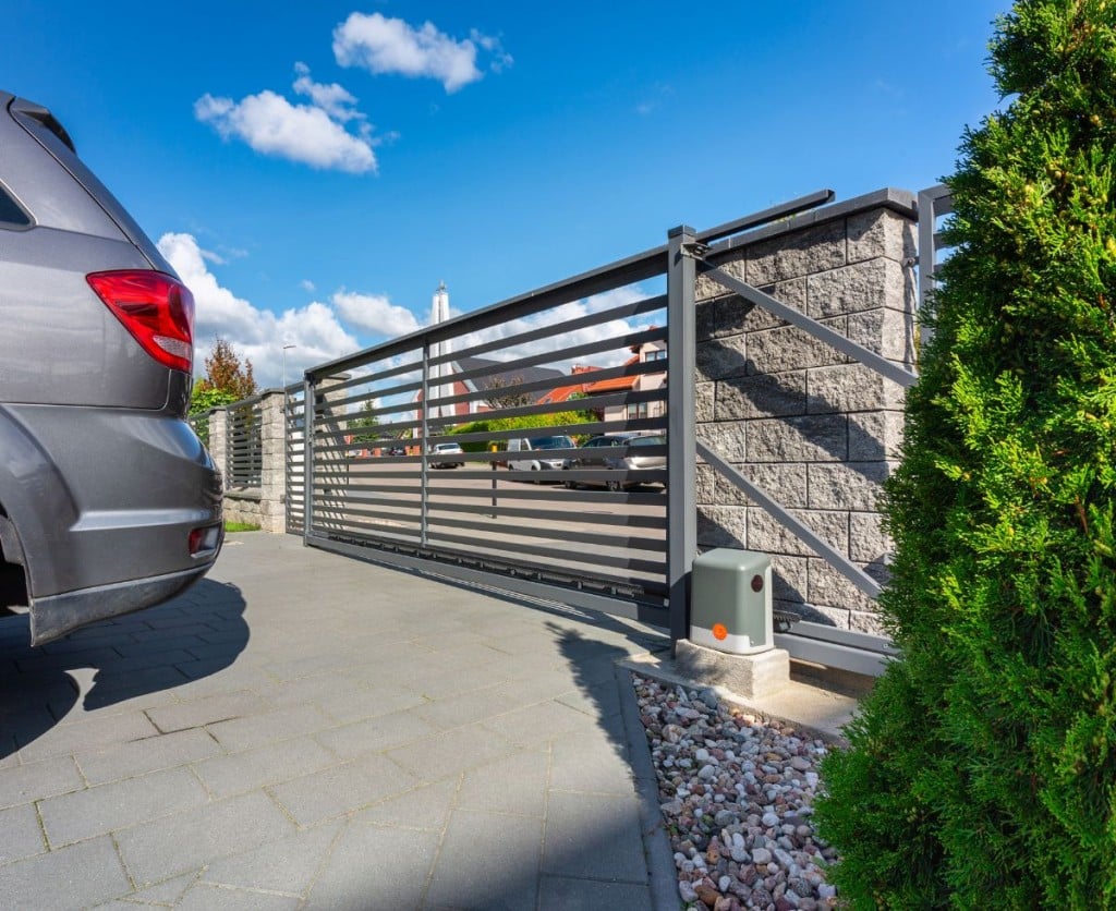 A parked car in front of a driveway gate. 
